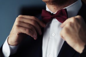 Man in a black suit fixing the collar of his dress.