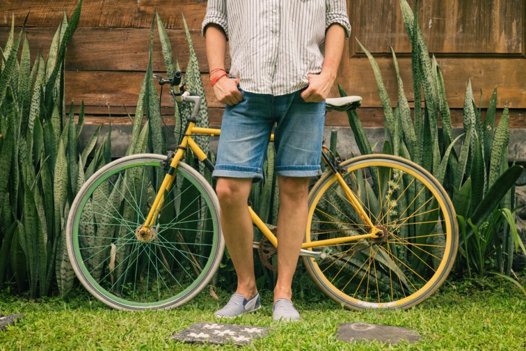 Styling with shorts - A man wearing denim shorts while standing in front of a bike.